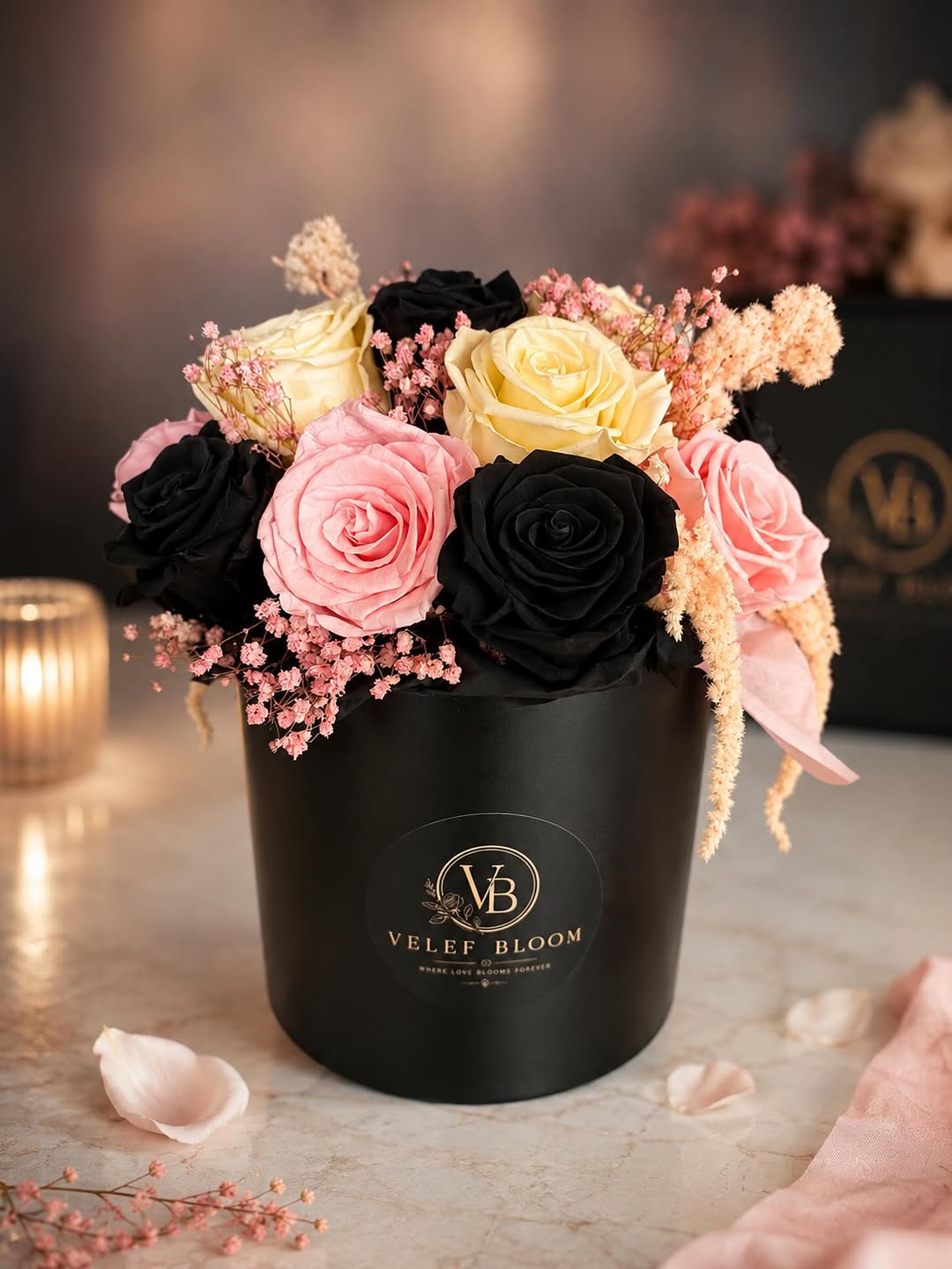Black, blush and cream preserved roses in a black Velef Bloom ceramic vessel, lit by candlelight